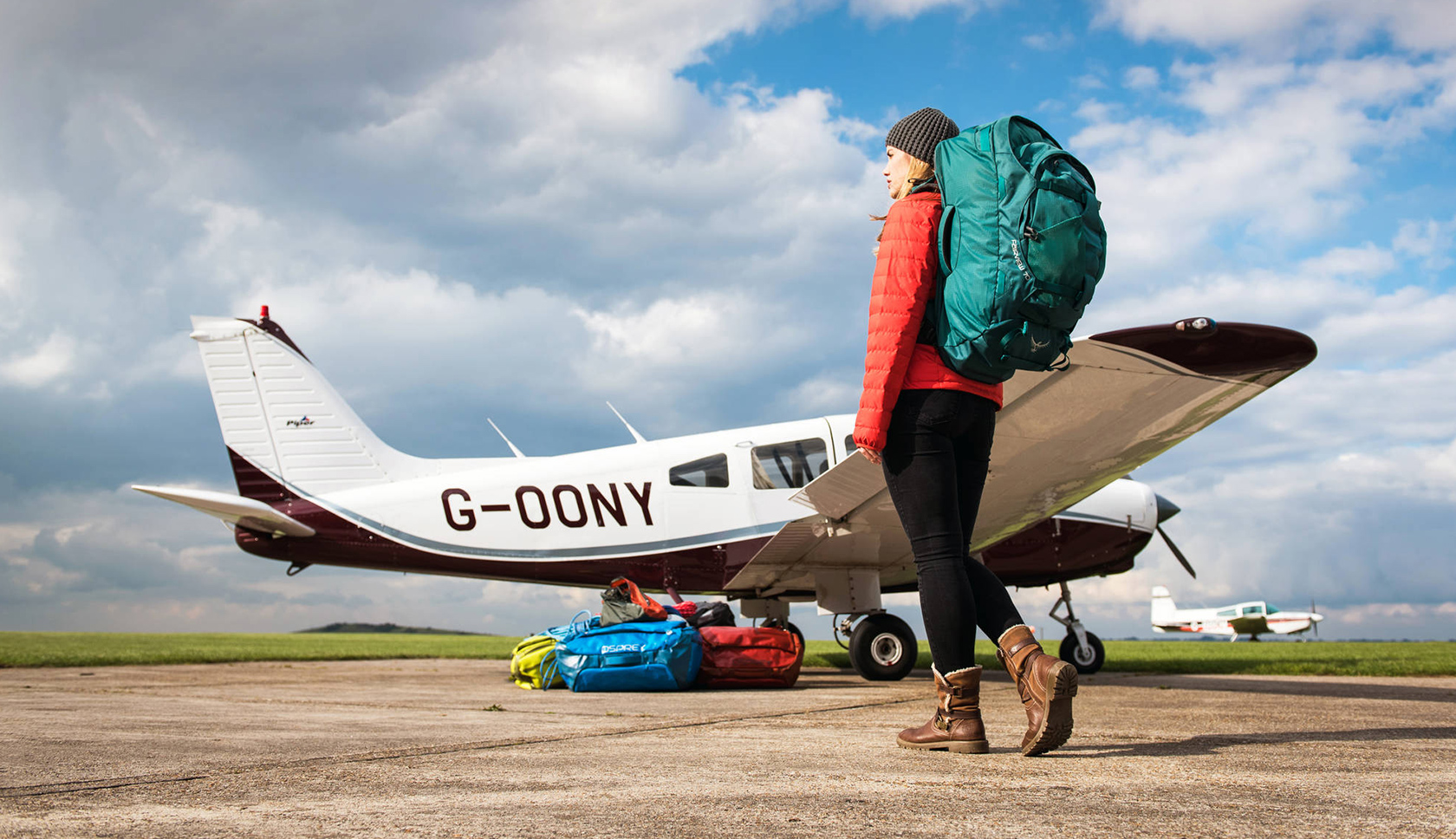 vrouw met osprey travelpack bij een vliegtuig