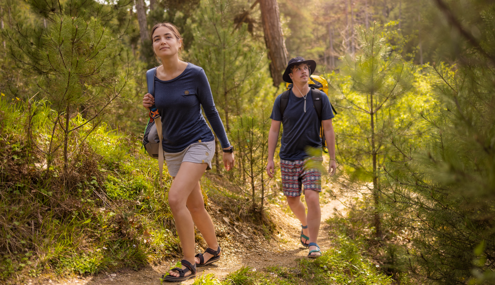man en vrouw hiken door een zonnig bos