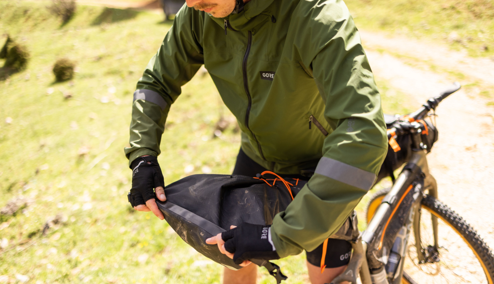 Iemand die aan het bikepacken is rolt zijn fietstas dicht.