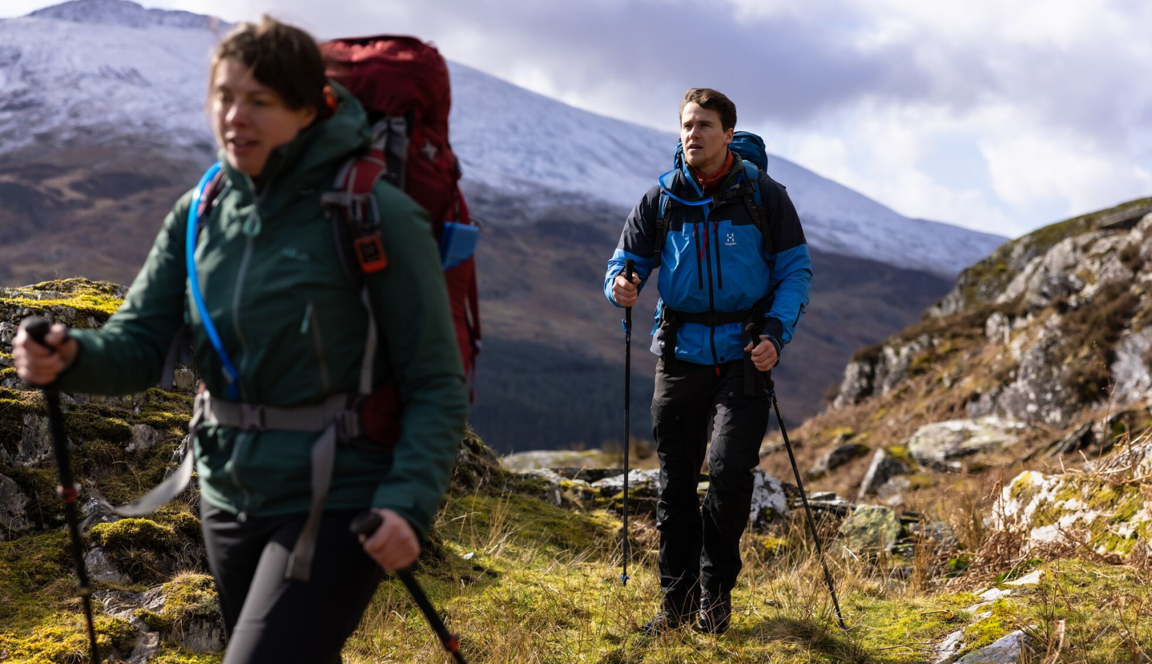 man en vrouw lopen bepakt door de bergen