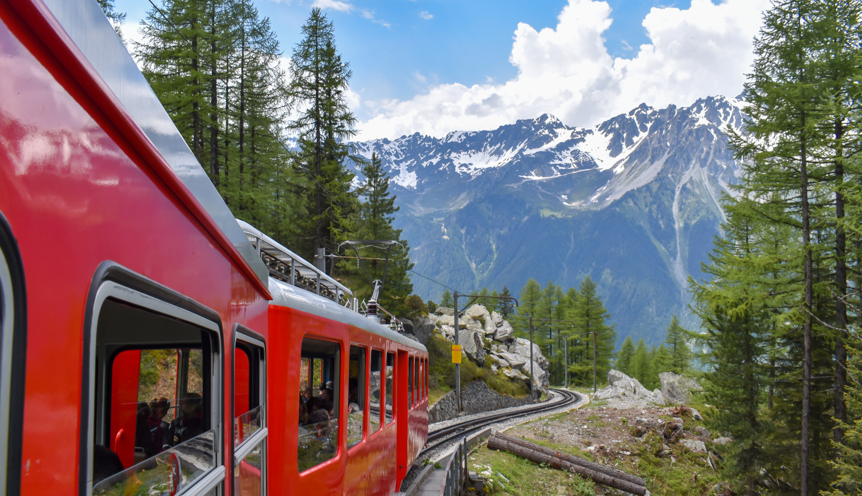 Een rode trein rijdt door berglandschap.