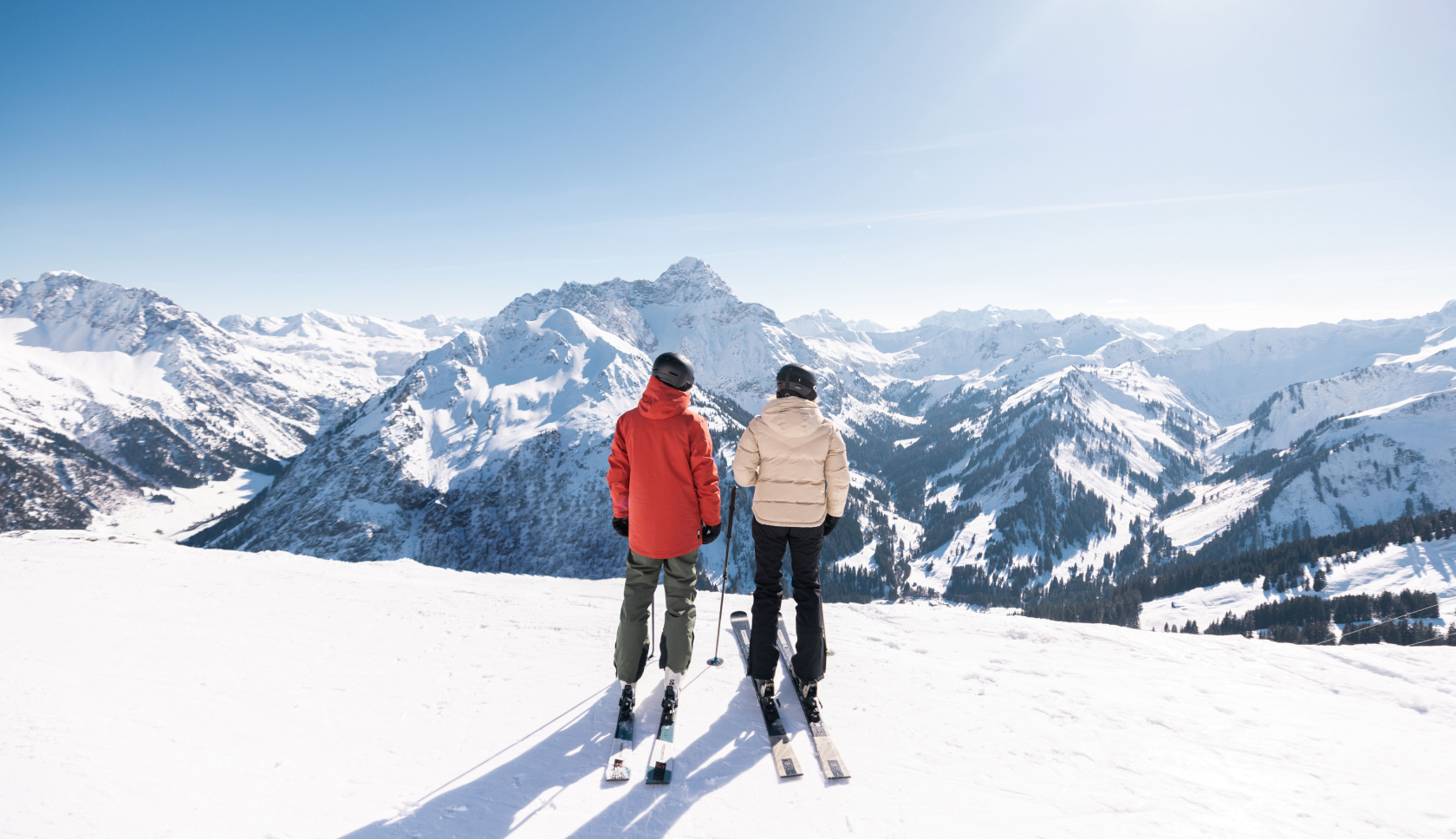 twee skier staan op een besneeuwde berg en kijken uit over bergachtig landschap