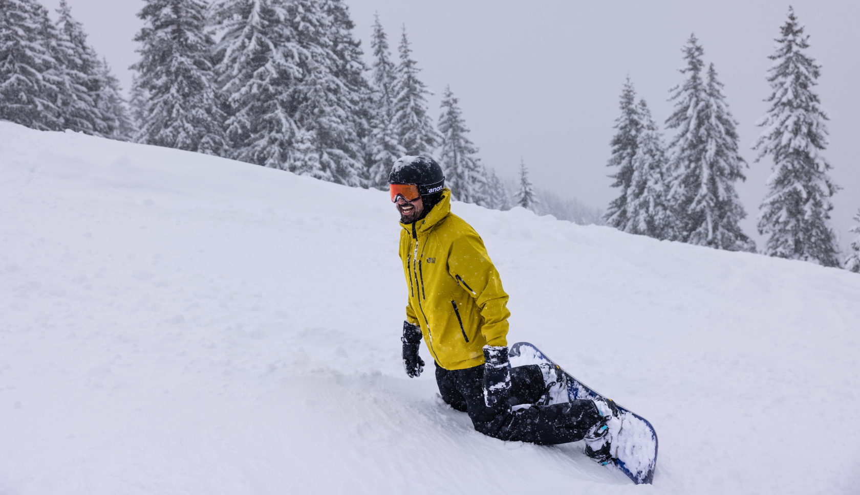 snowboarder zit op z'n knieen in de sneeuw