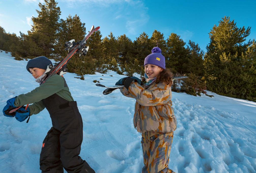 kinderen lopen met ski's door de sneeuw