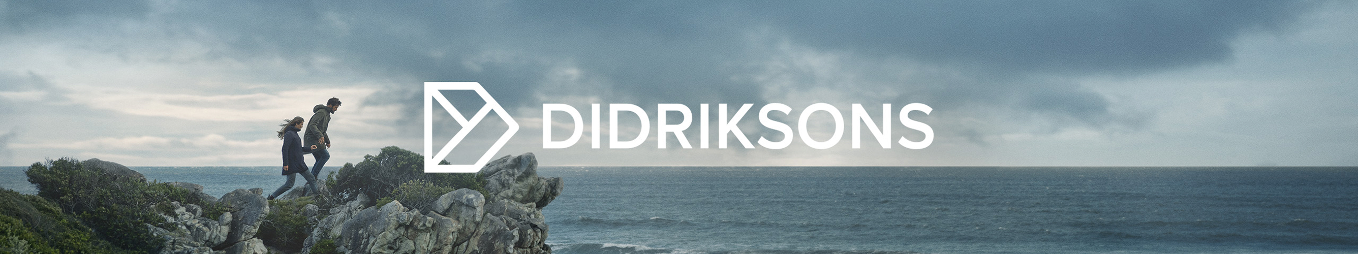 twee mensen op een rots, wind in de haren, met uizicht op zee