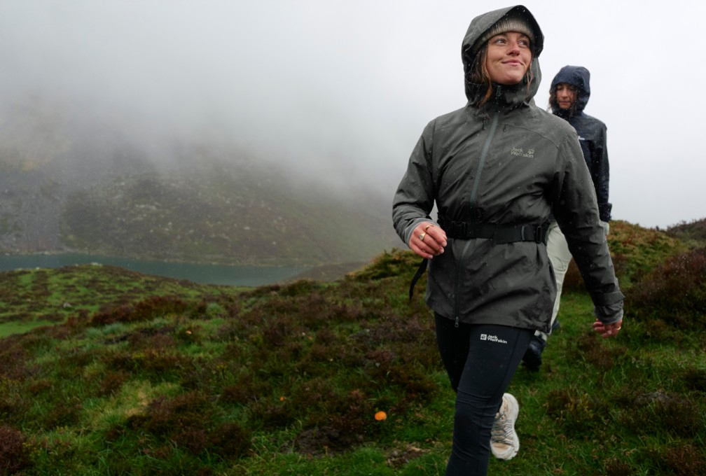 vrouw wandelt door de bergen in regenkleding
