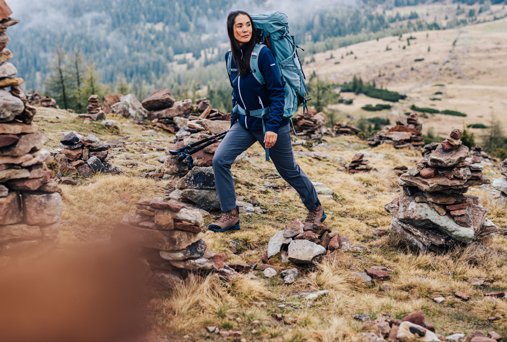 vrouw met backpack wandelt over rotsachtige heuvel