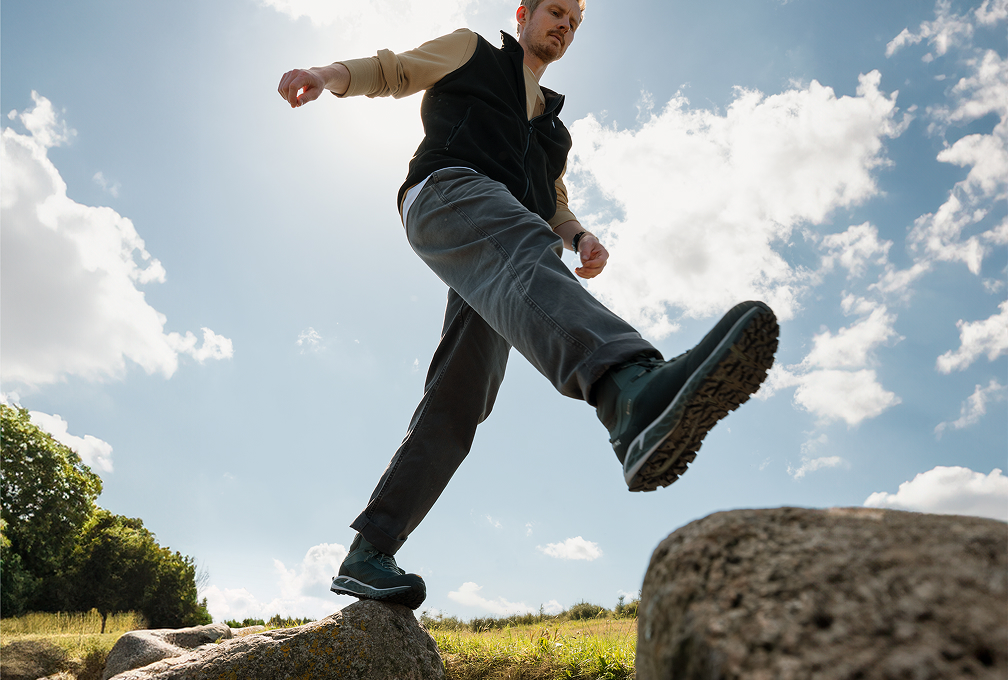 foto van onder, man balanceert op rotsen op een groen veld
