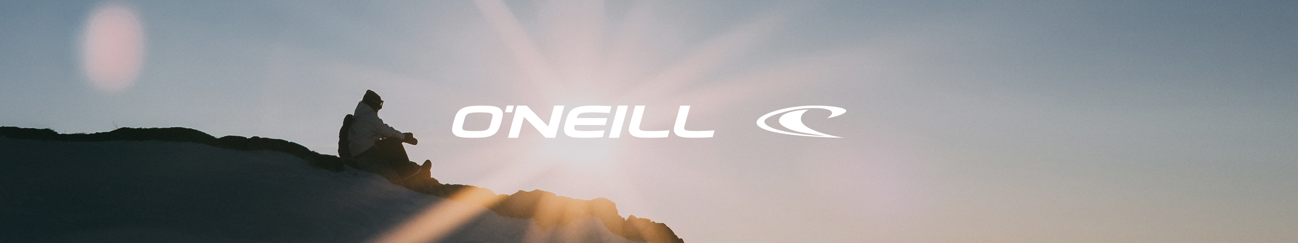 man zit op een rots met de felle zon achter hem