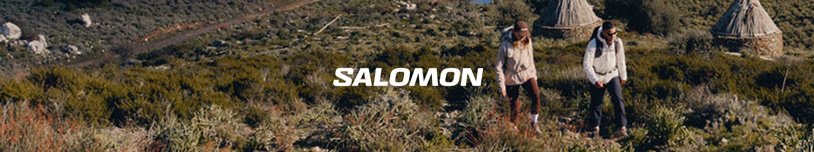 twee mensen lopen voor hun tenten omringd door bergen