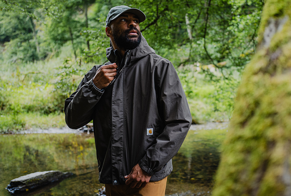 Man in een zwarte Carhartt jas tijdens een wandeling in het bos